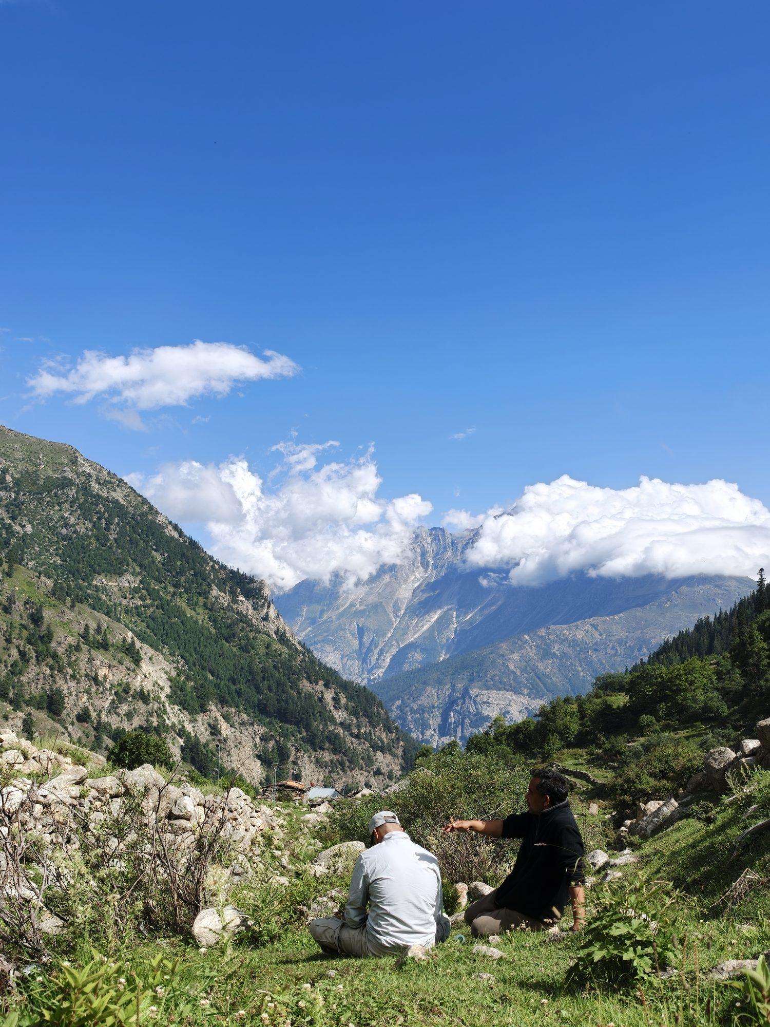 Two guests resting on the slope, one pointing out across the valley