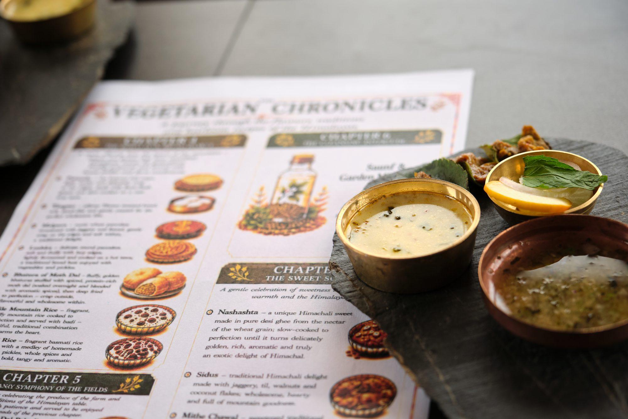 The printed Vegetarian Chronicles menu beside the brass bowls
