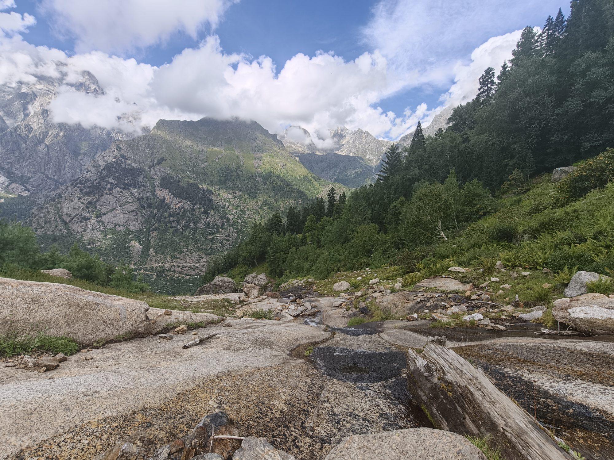 Bare granite slabs and a shallow stream below the peaks