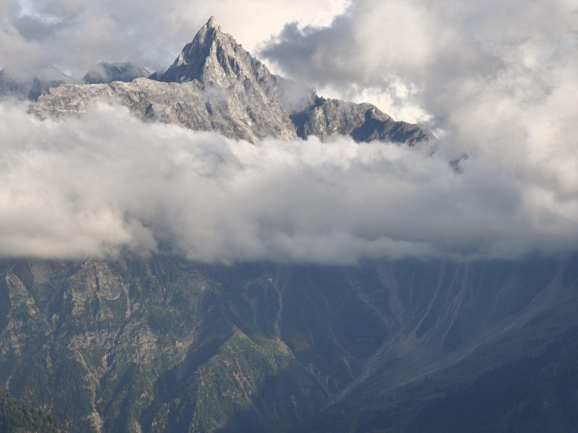 The granite spire of Kinner Kailash sunlit above a level bank of cloud