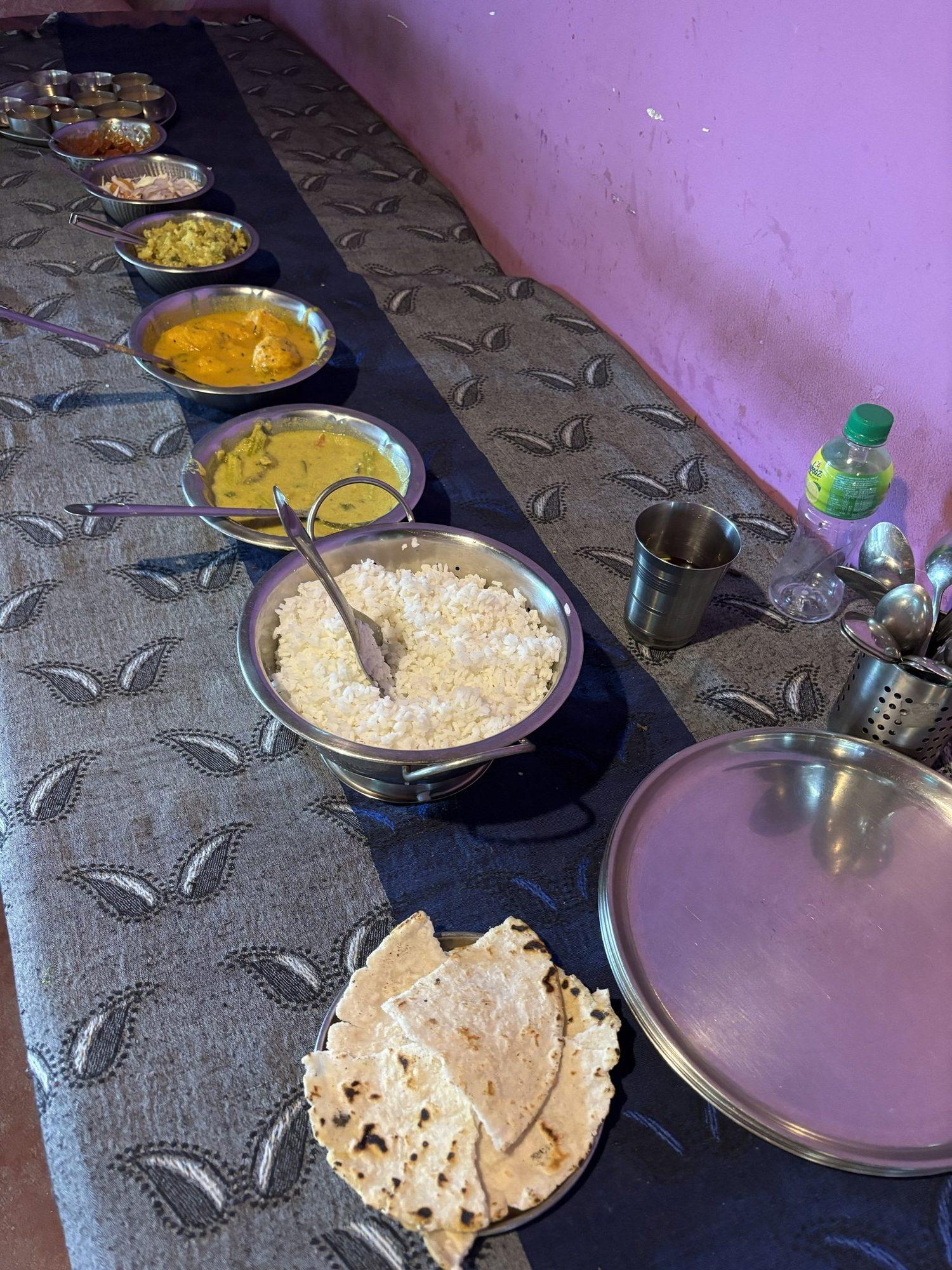 A Goan thali of rice, curries and poee laid out on the mat