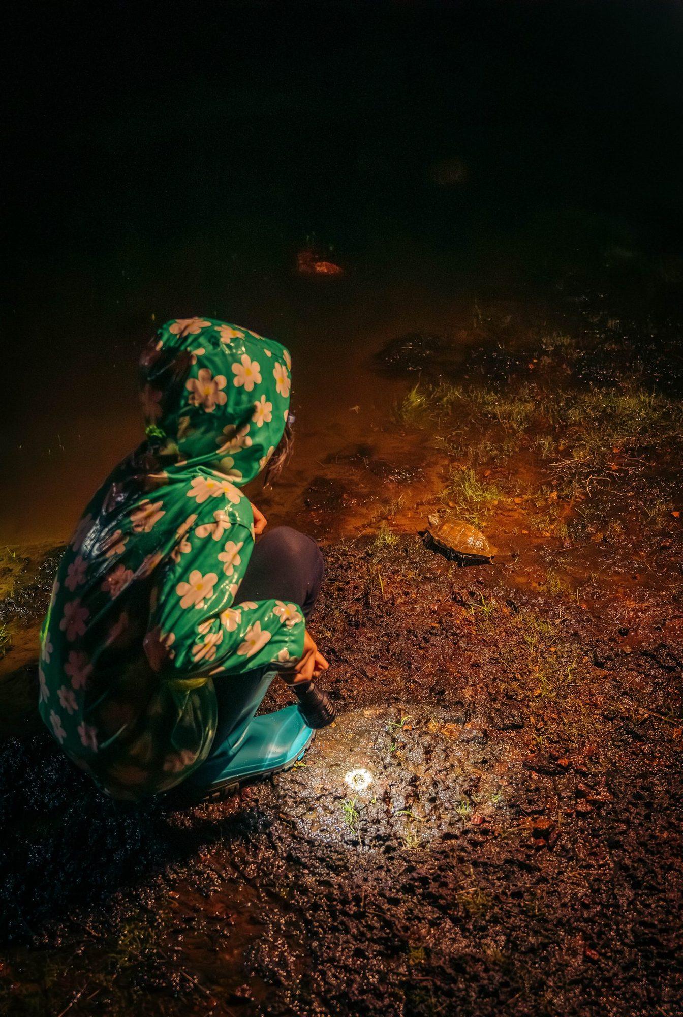 A child crouching with a torch on the red laterite