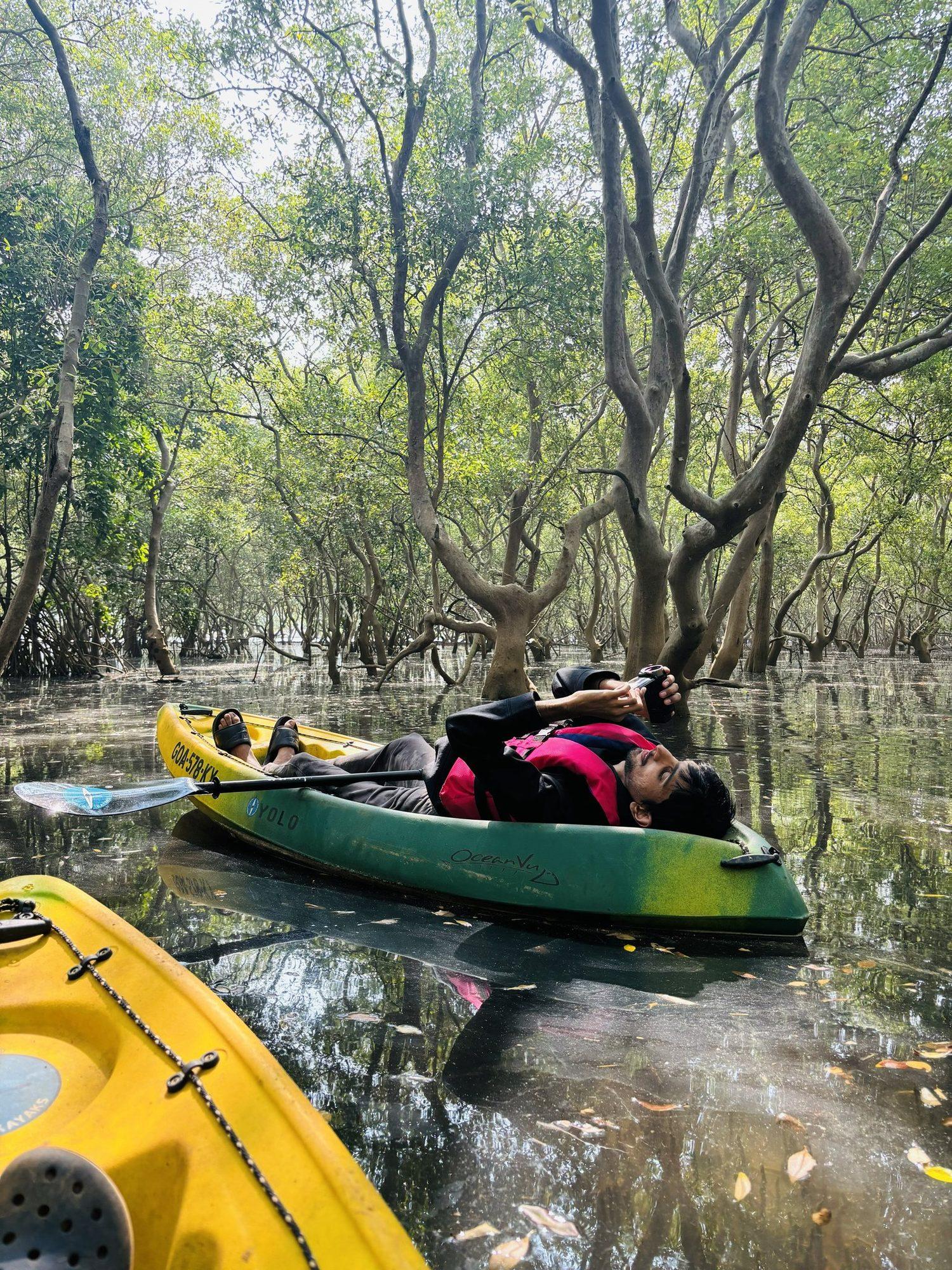 A kayaker lying back among the mangrove roots