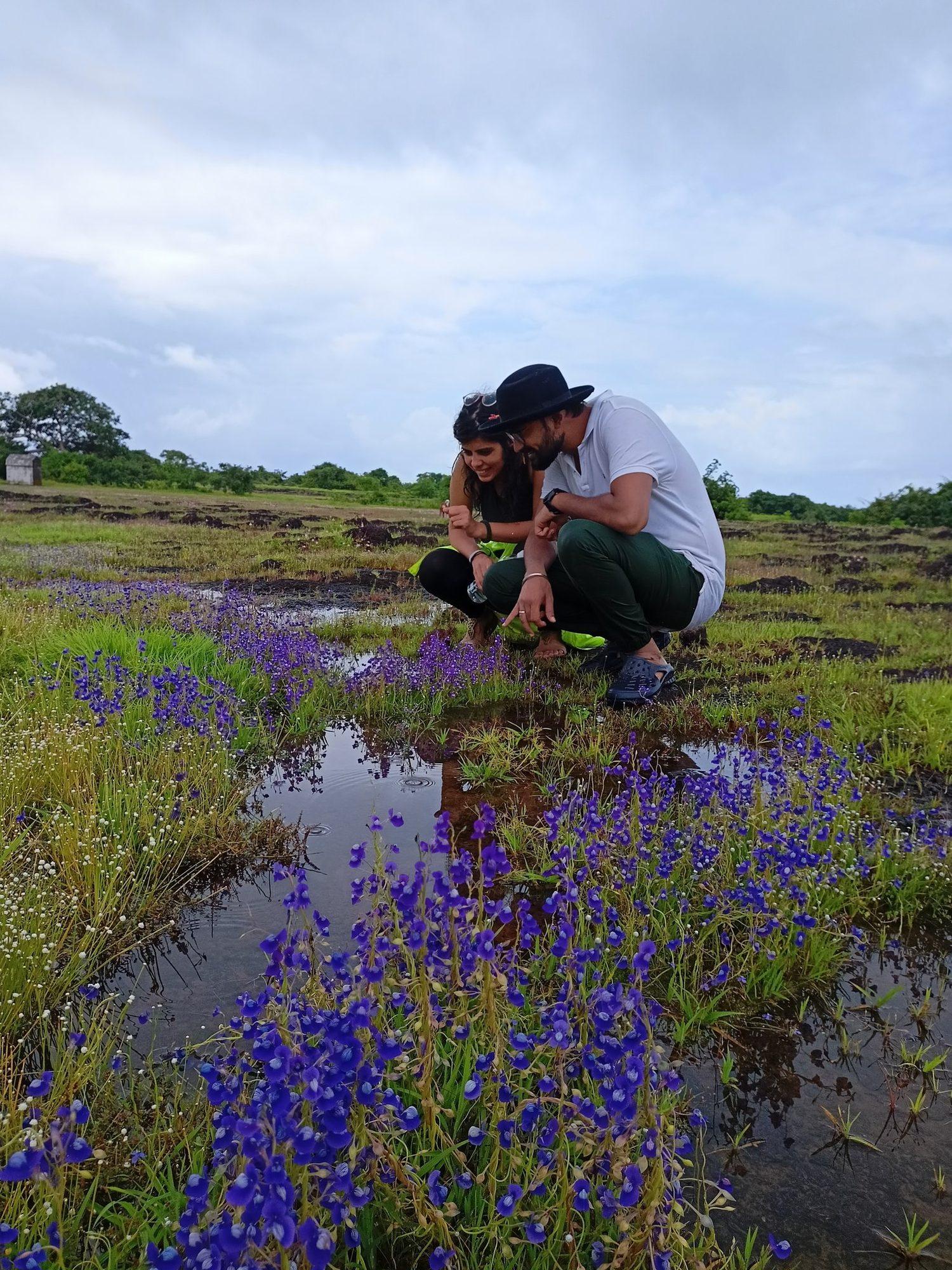 Two guests crouching beside the wildflowers at the water's edge