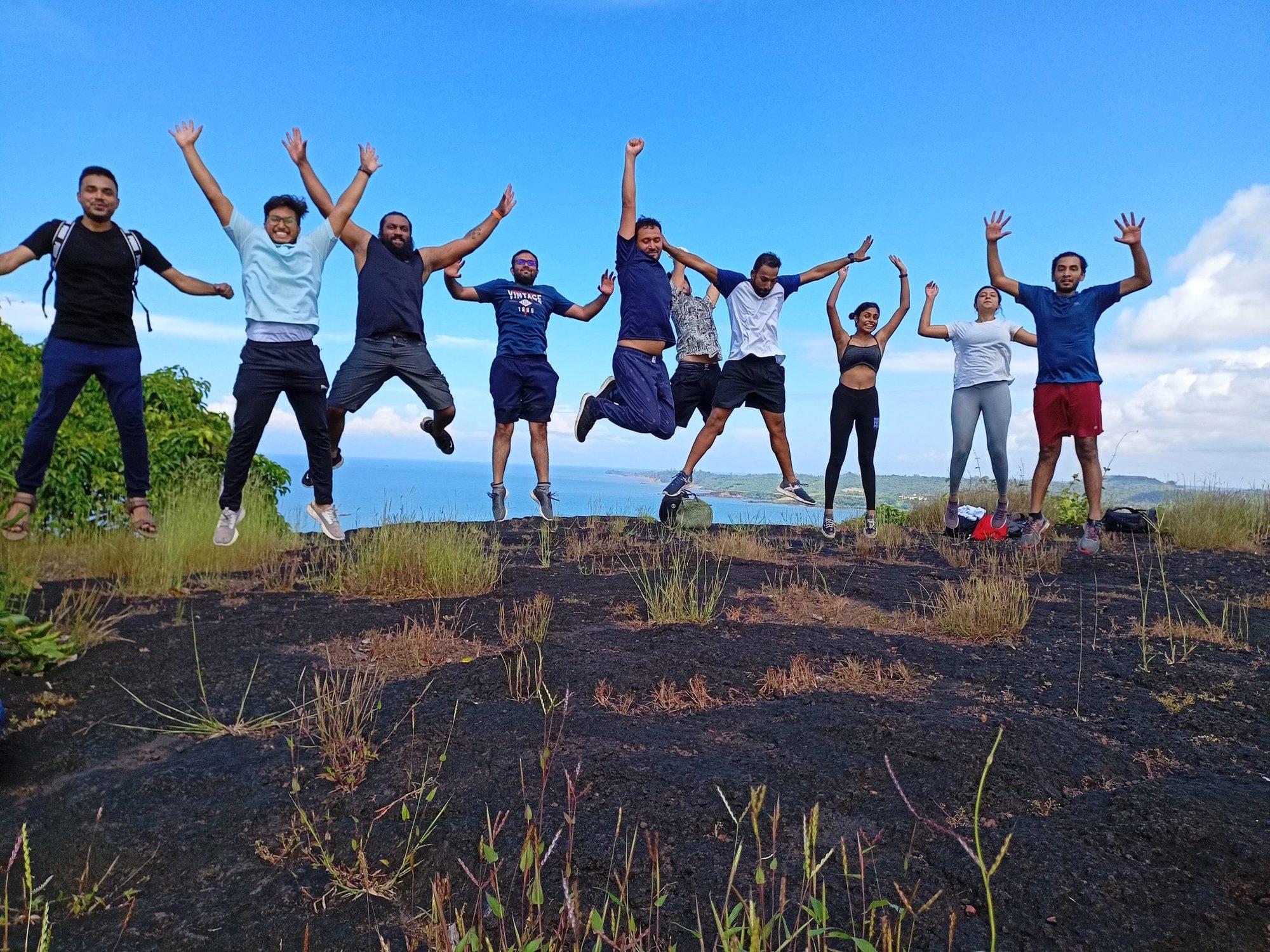 The group jumping on the plateau rock with the sea behind