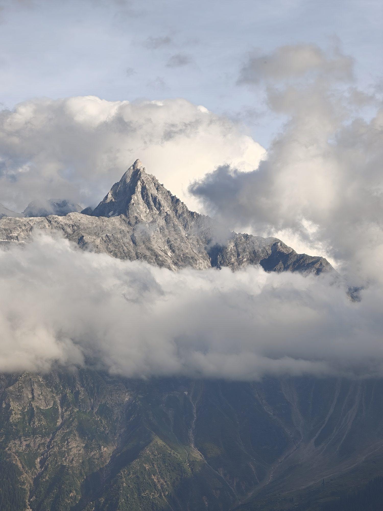 The granite spire rising sunlit through a thick bank of cumulus