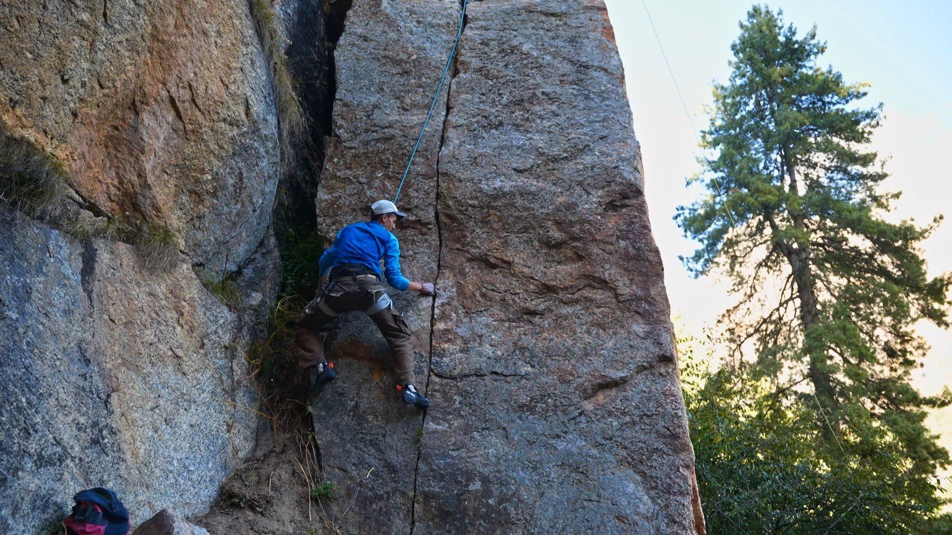 A climber on a roped route up the granite crack