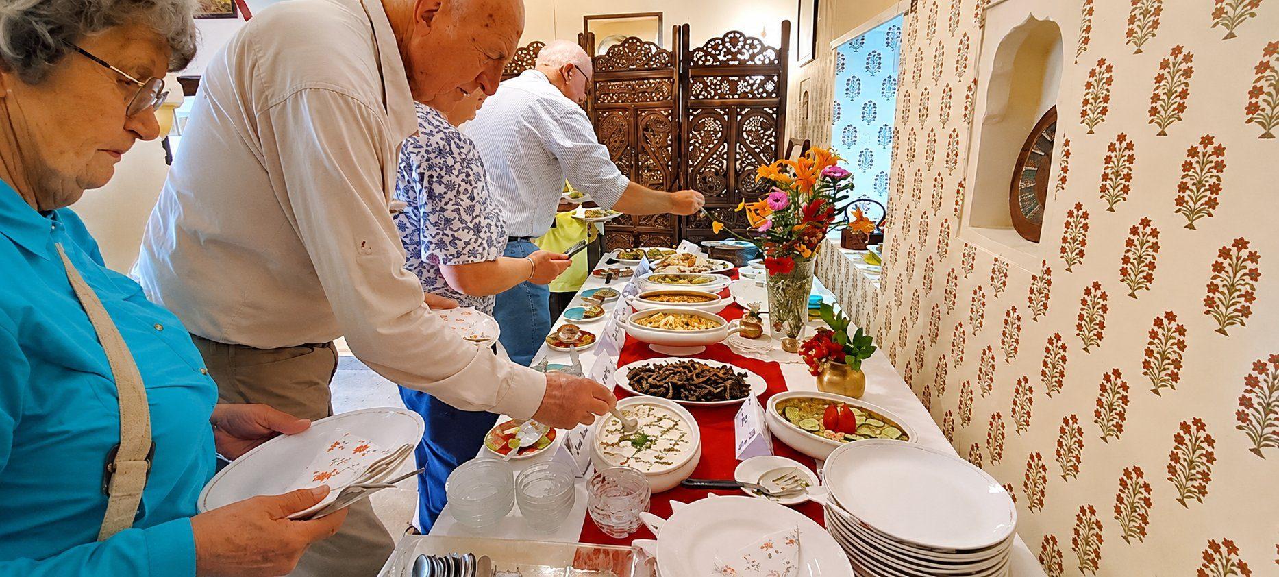 Guests serving themselves from the long buffet against a block-printed wall