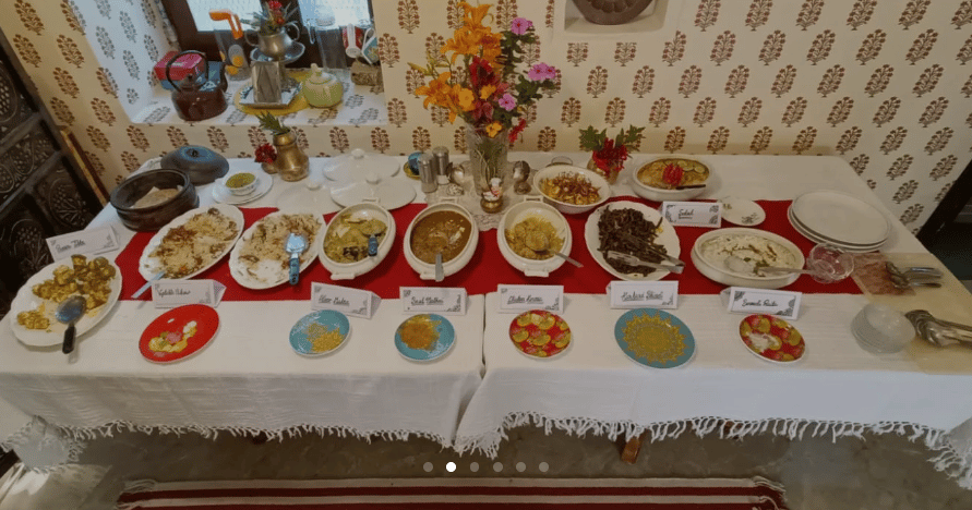 The dining table laid end to end with labelled Himachali dishes and flowers