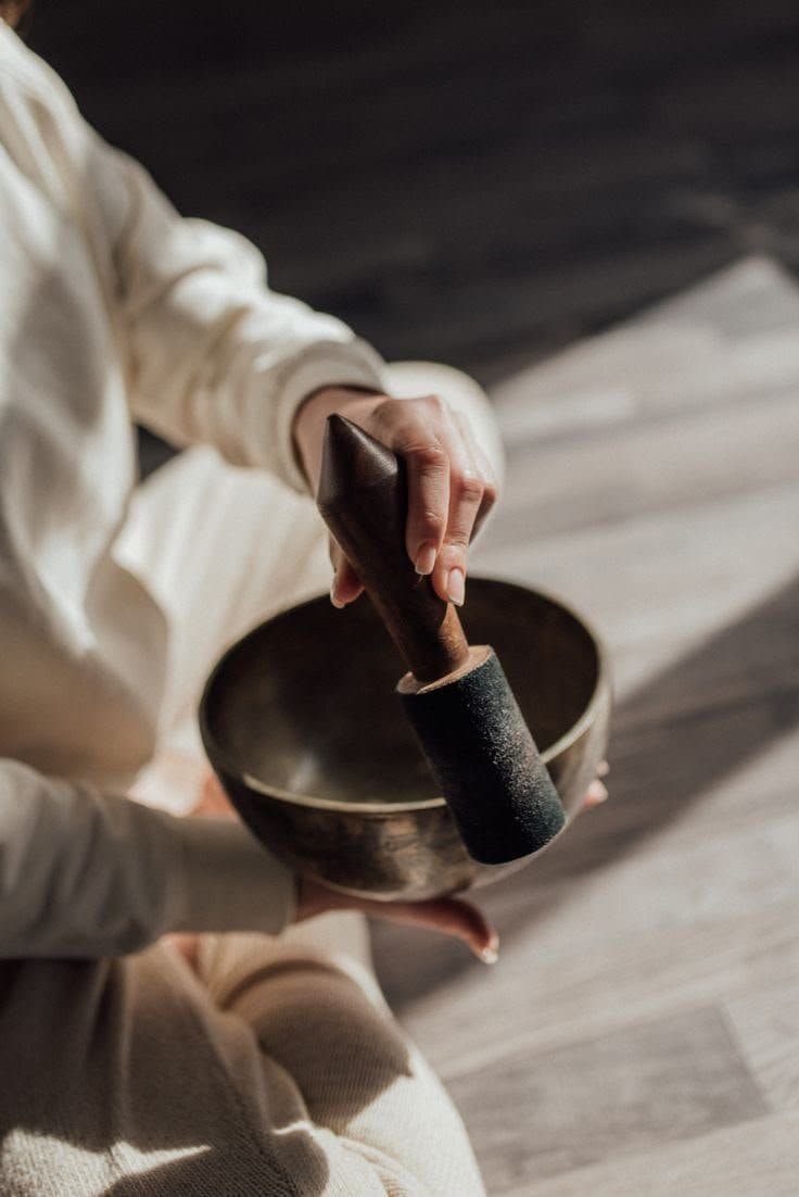 Hands working a singing bowl with the mallet