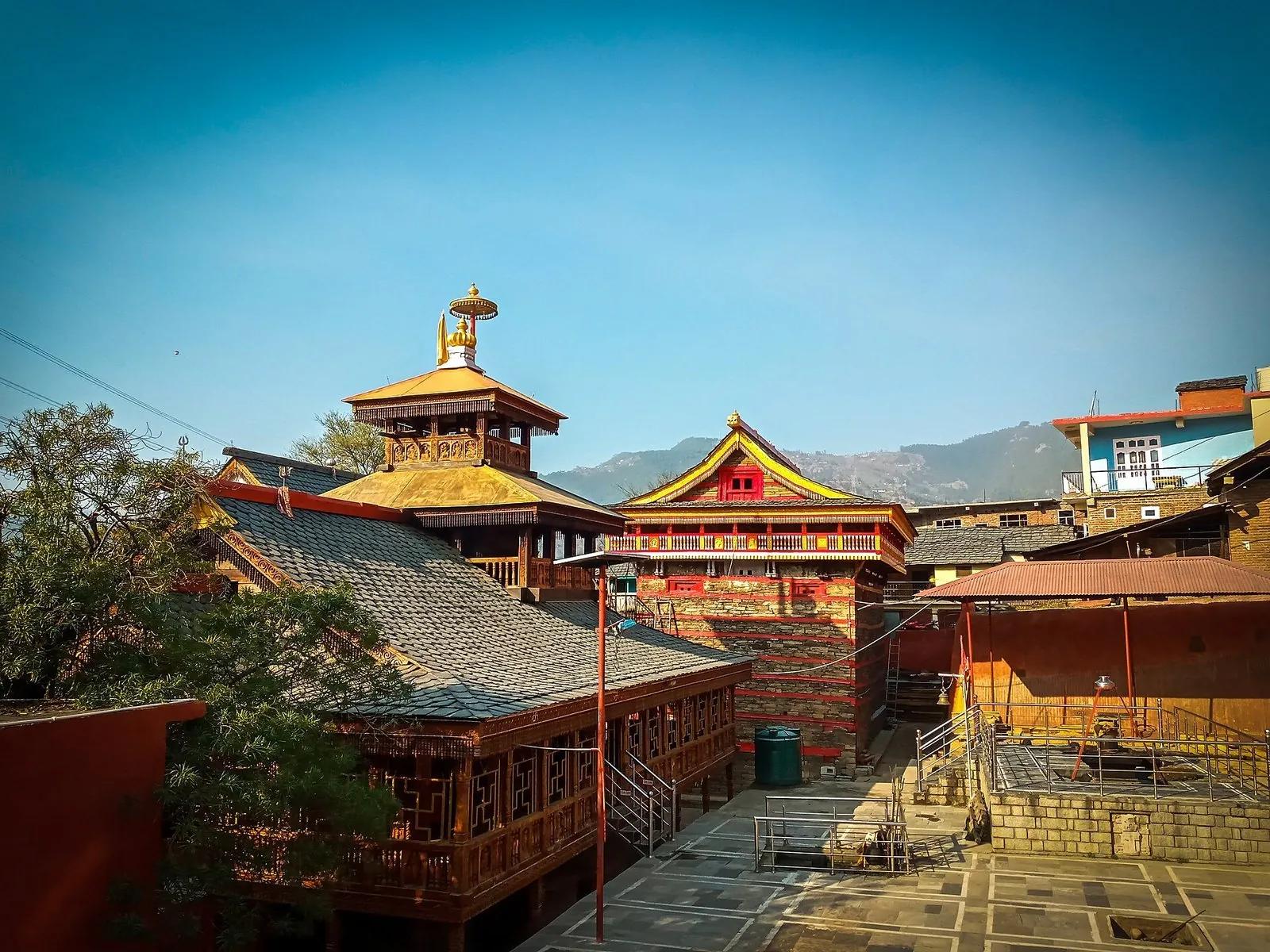 Mamleshwar Mahadev temple complex in Mamel, Karsog, with a gilded kath-kuni pagoda, a red and gold gabled shrine and slate roofs against the valley hills