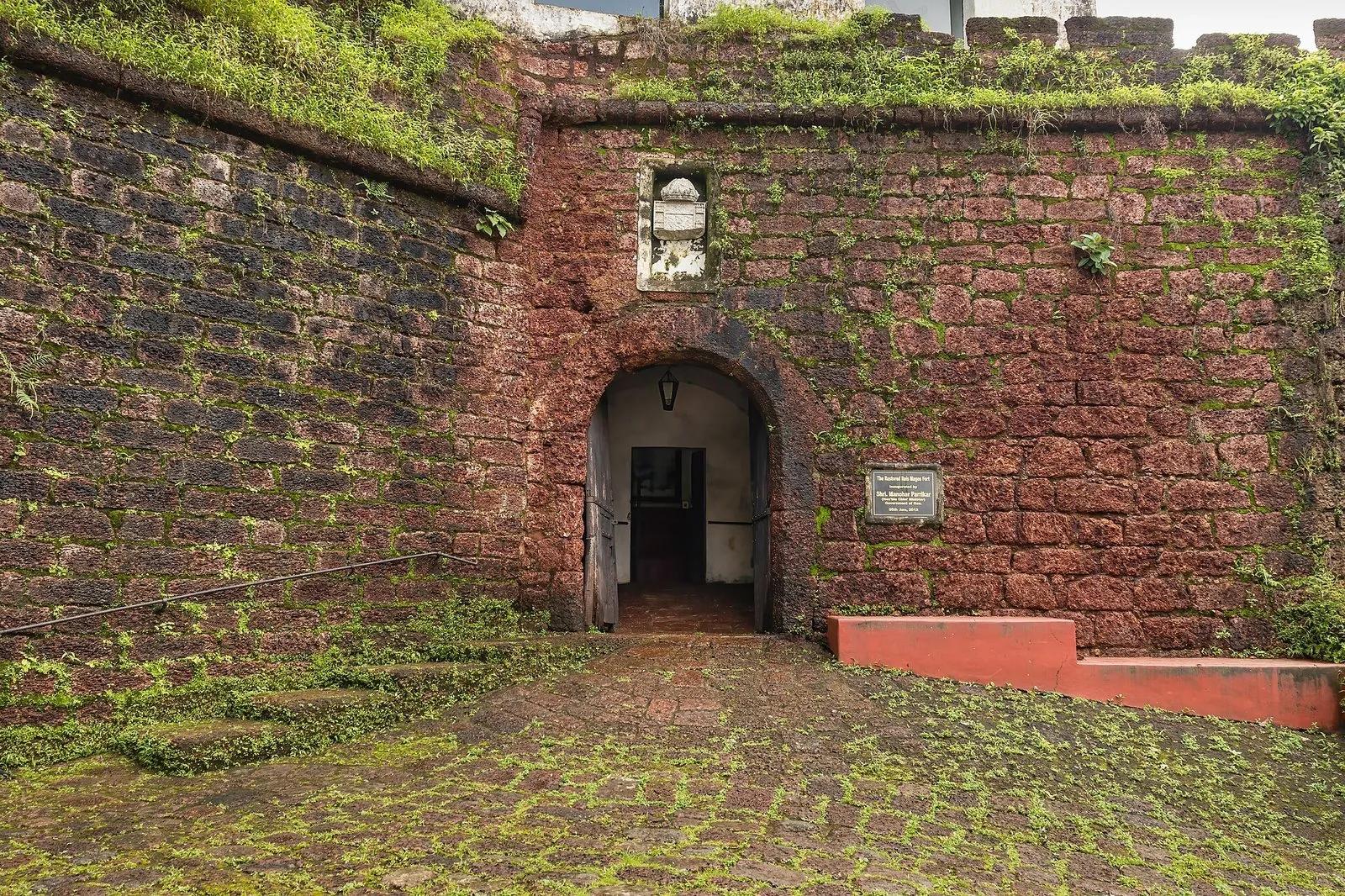 The mossy red-laterite entrance archway of Reis Magos Fort in Goa