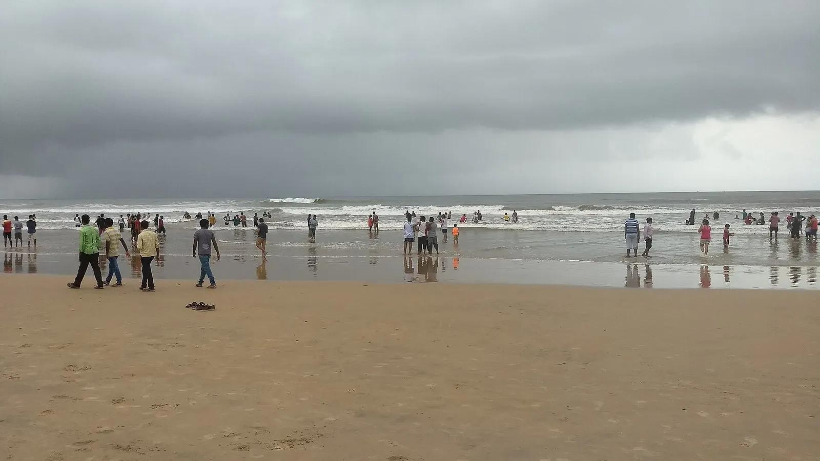 A grey, overcast Baga beach in the monsoon with a rough brown sea and dark storm clouds