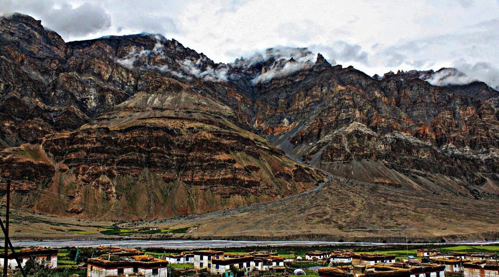 Wide remote Himalayan landscape with a tiny village beneath towering cliffs in Lahaul-Spiti, evoking how far you are from the nearest cell tower