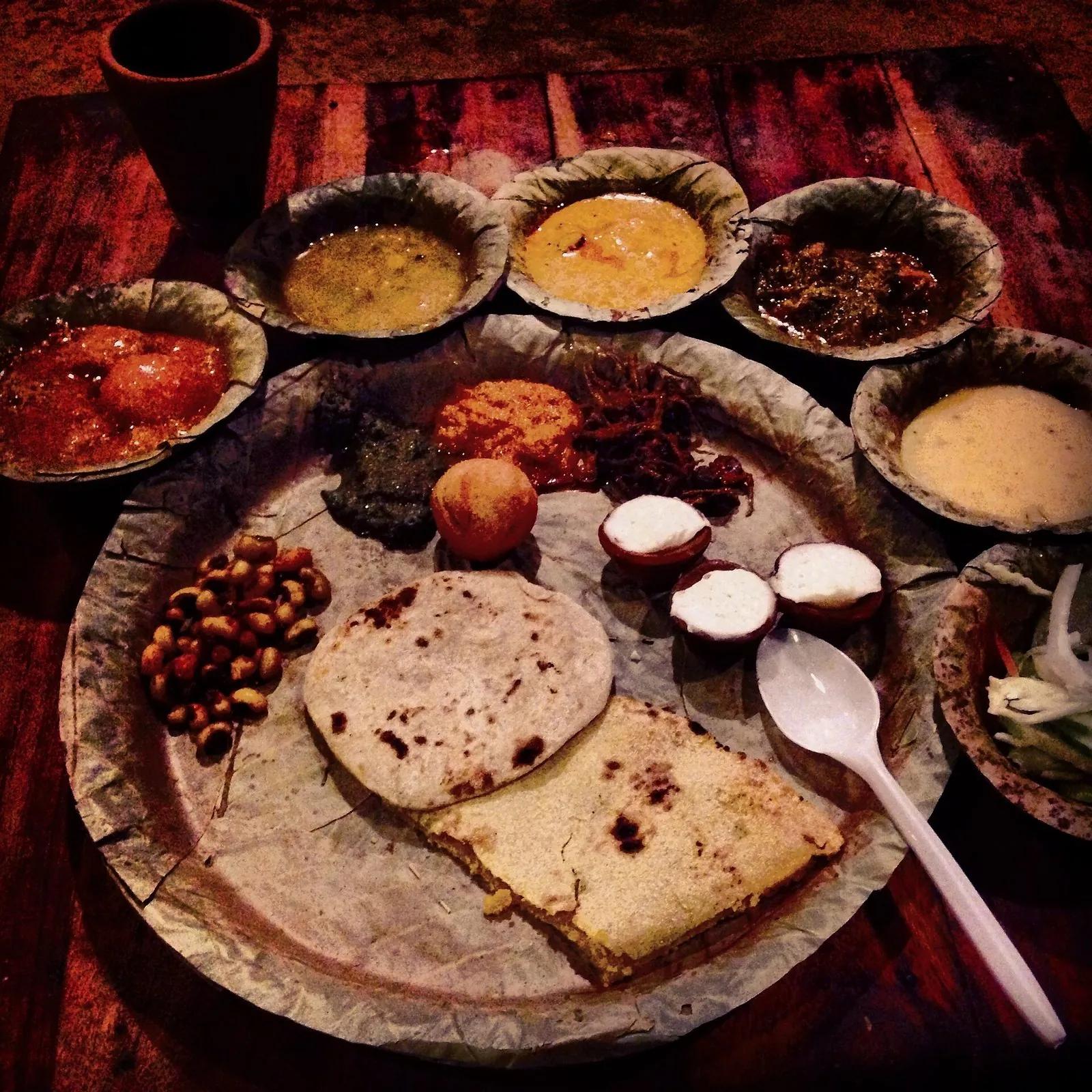 A Rajasthani thali on a stitched-leaf plate with dal, kadhi, curries, baati and churma
