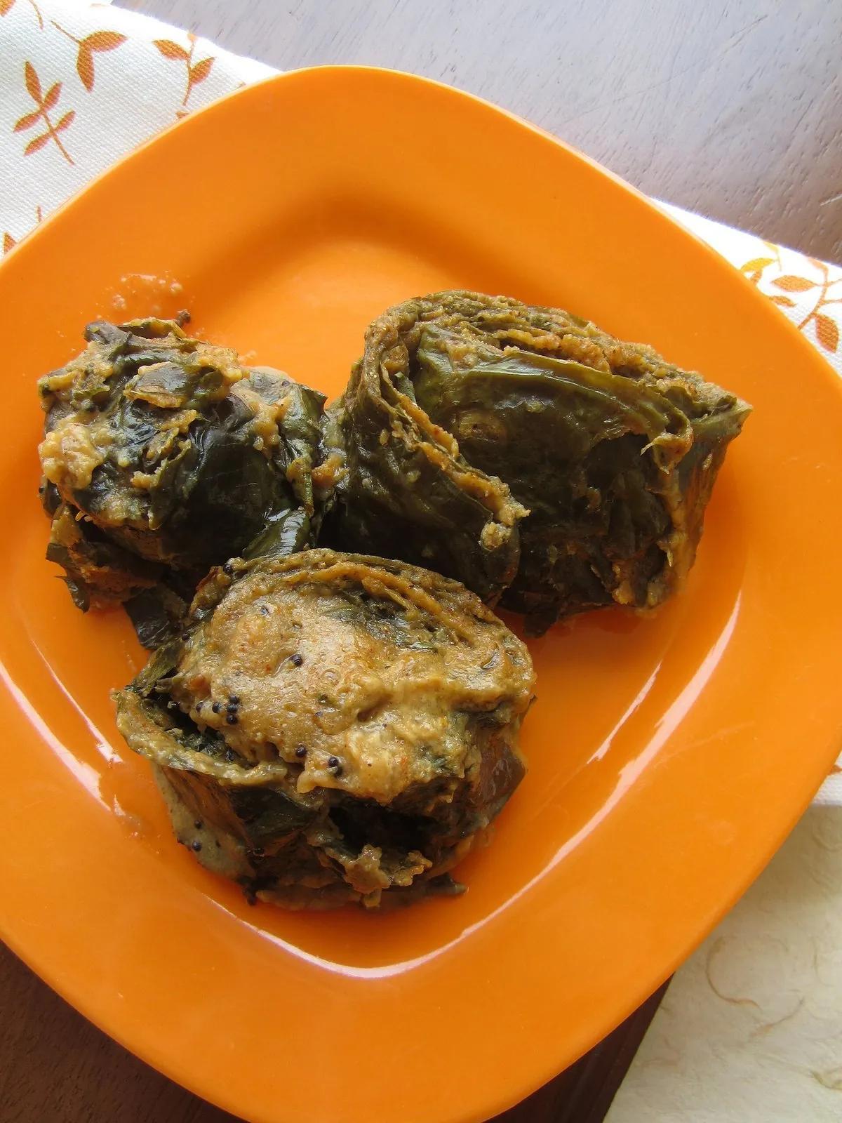 Sliced patrode rolls showing the spiral of colocasia leaf and spiced gram paste on an orange plate