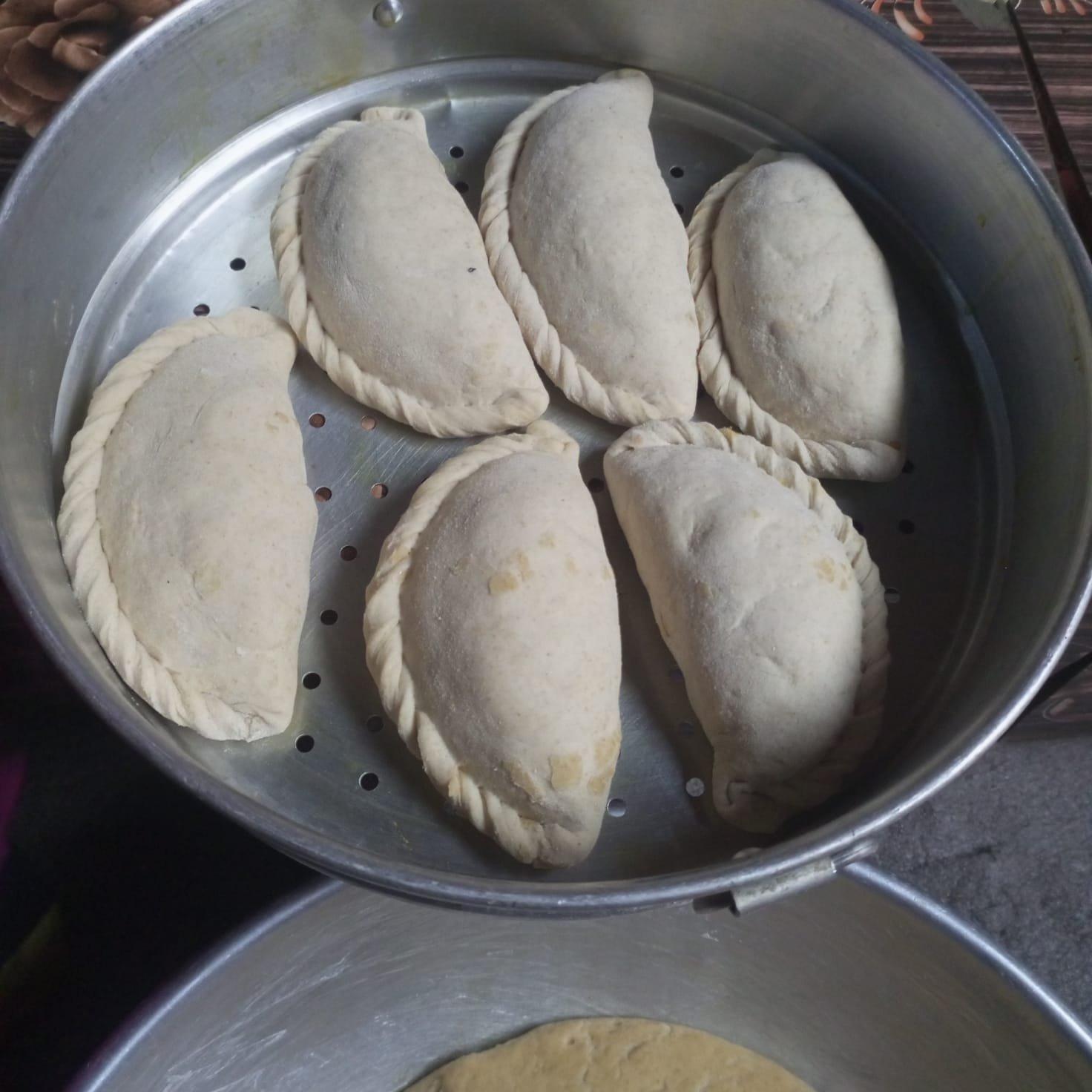Seven freshly steamed siddu in a steel steamer, the half-moon Himachali stuffed bread Kullu calls its own