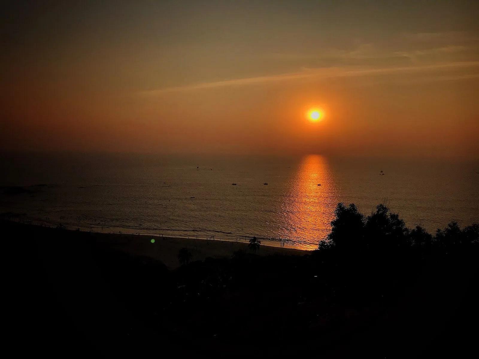 A wide golden sunset over the sea seen from an elevated viewpoint at Chapora fort, Goa