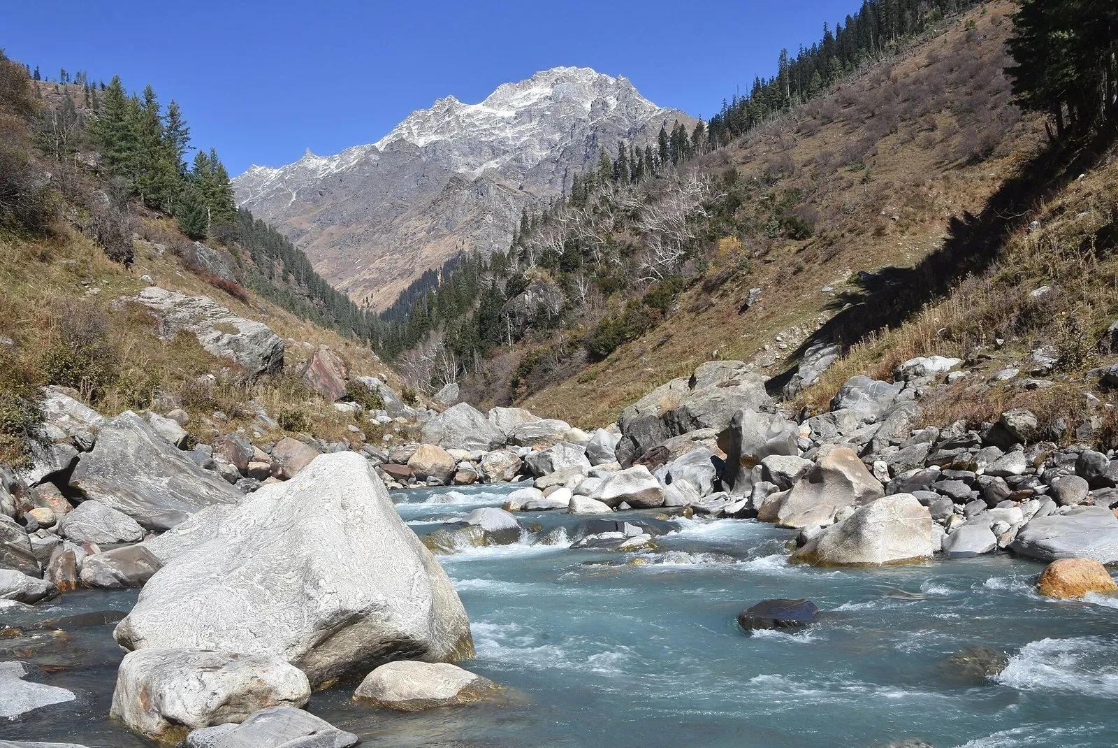 The Parvati river running clear past boulders below a snow peak in the upper Parvati Valley above Kasol