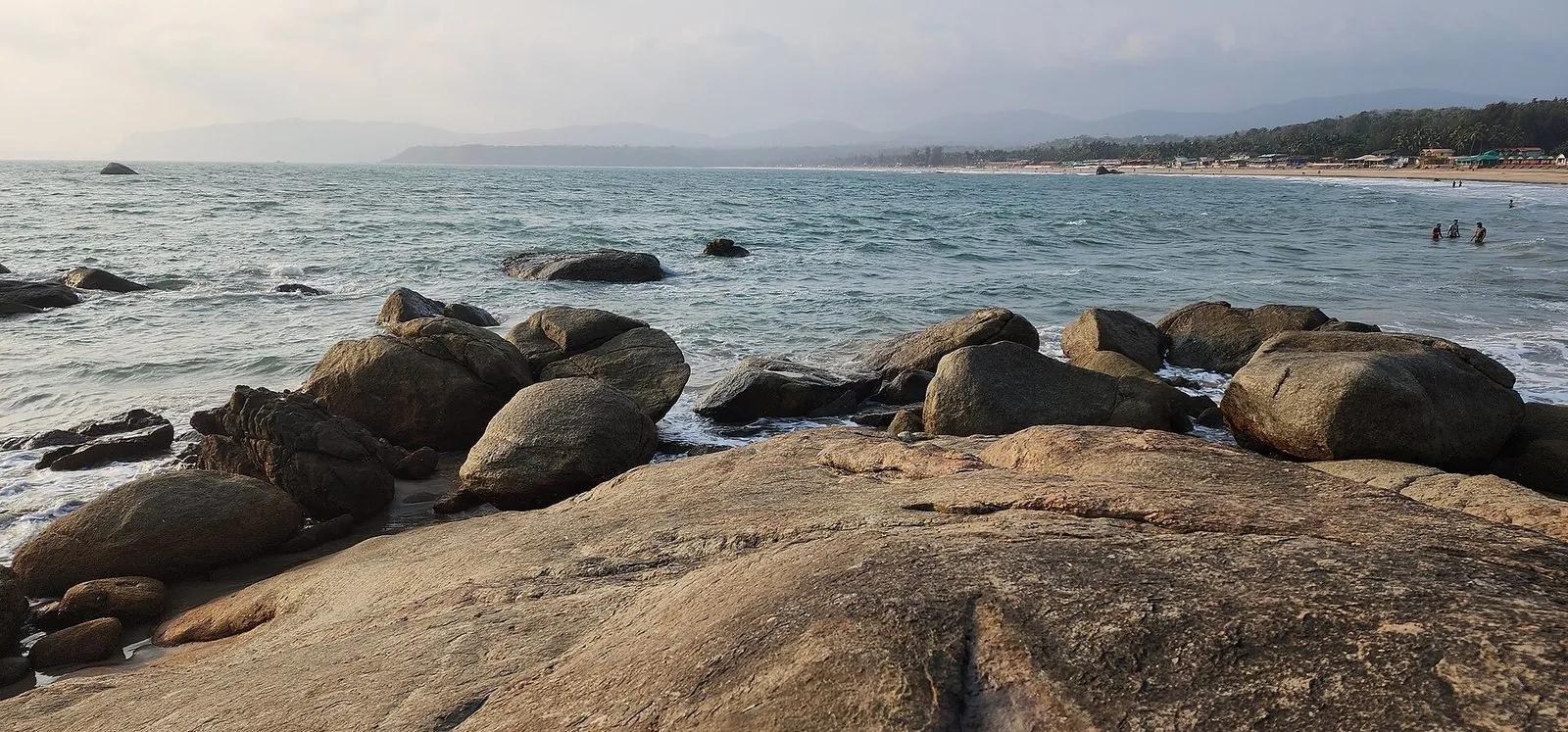 A calm, quiet evening on Agonda beach in South Goa, rocks in the foreground and a gentle sea