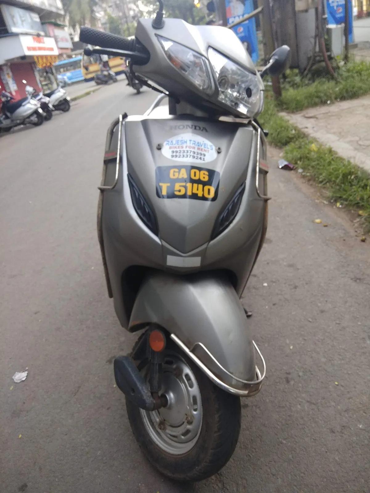 A rented grey Honda Activa scooter with a yellow tourist number plate and a bike-rental shop sticker, parked on a Goa street