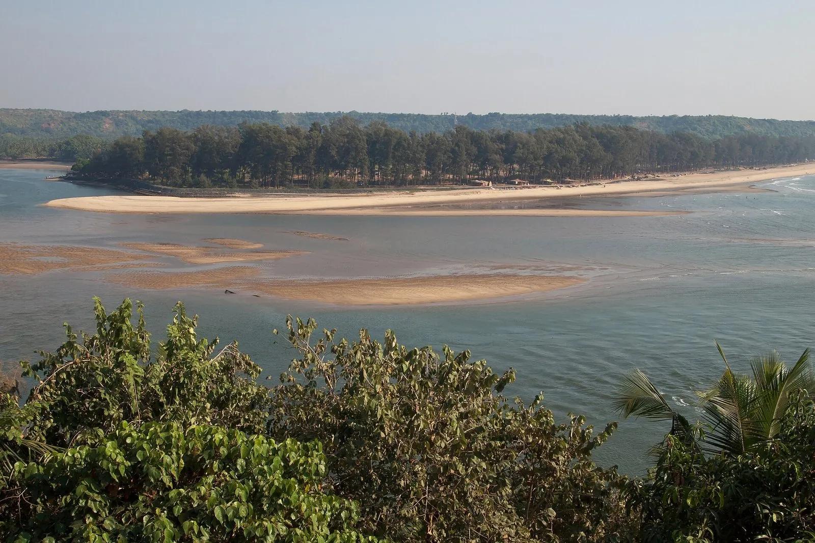 A panoramic view of the Terekhol river meeting the sea at the empty sandbar of Querim beach, North Goa