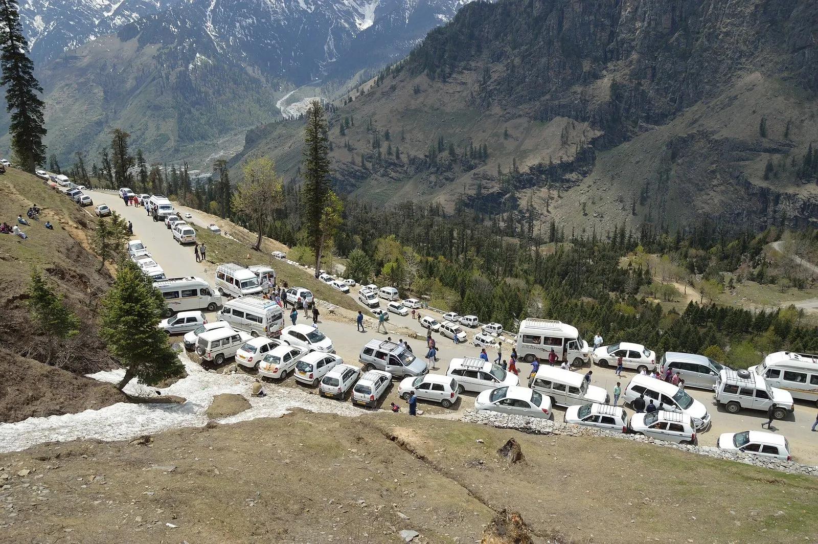 Dozens of white tourist taxis jammed bumper to bumper at Gulaba on the Manali-Rohtang road in peak season, tourists walking between stopped vehicles