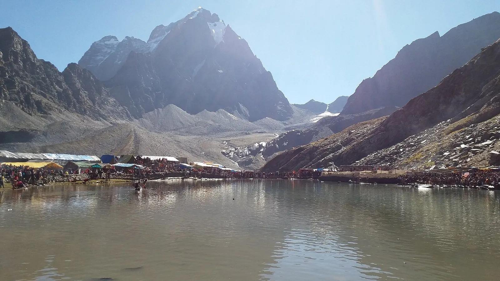Manimahesh Lake with Manimahesh Kailash Peak rising behind, yatra encampment on the lake shore