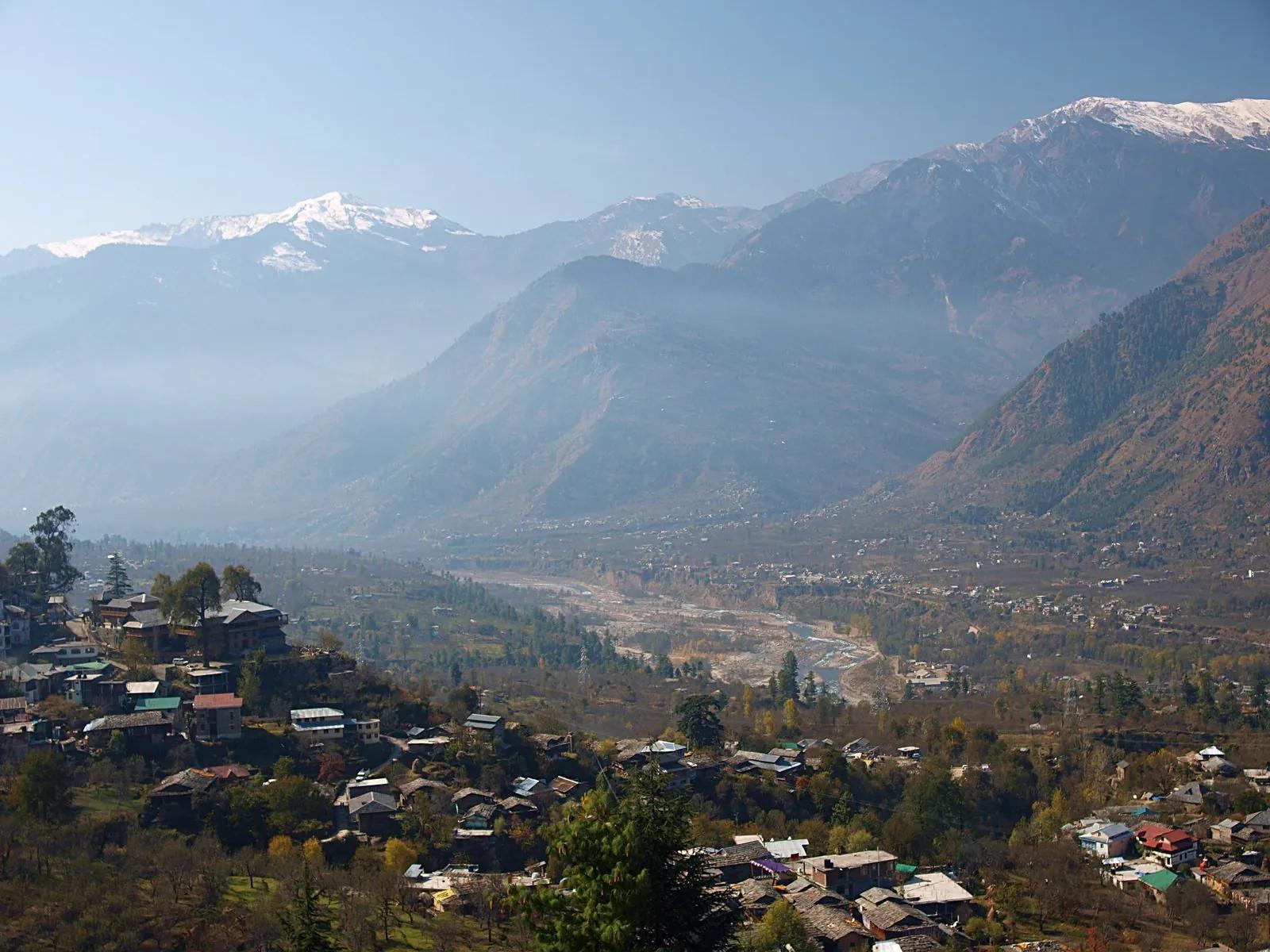Snow-capped Himalayan peaks behind Kullu valley villages, the sunrise landscape bus passengers wake up to on the final stretch to Manali