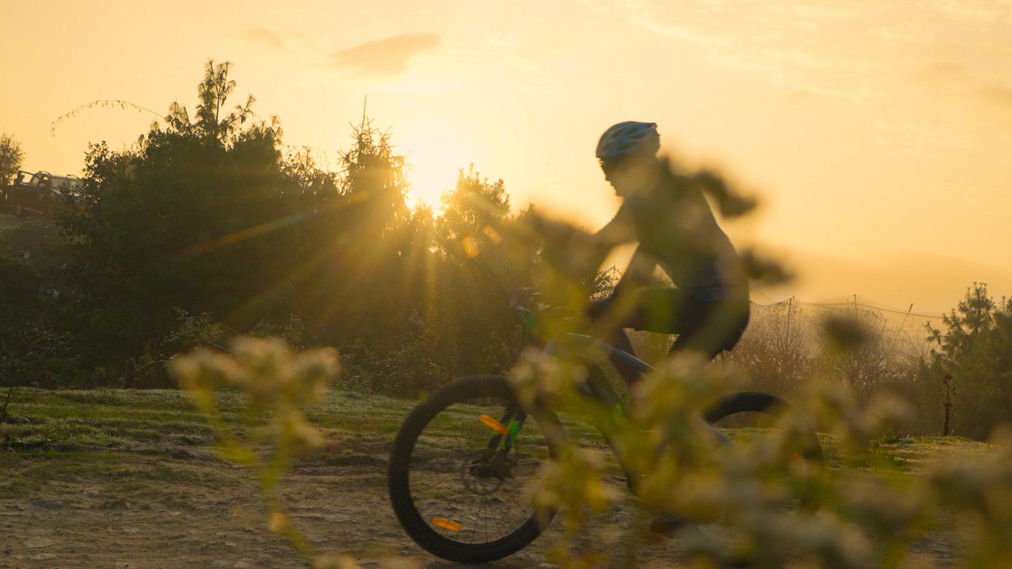 A cyclist riding through the mountains at golden hour