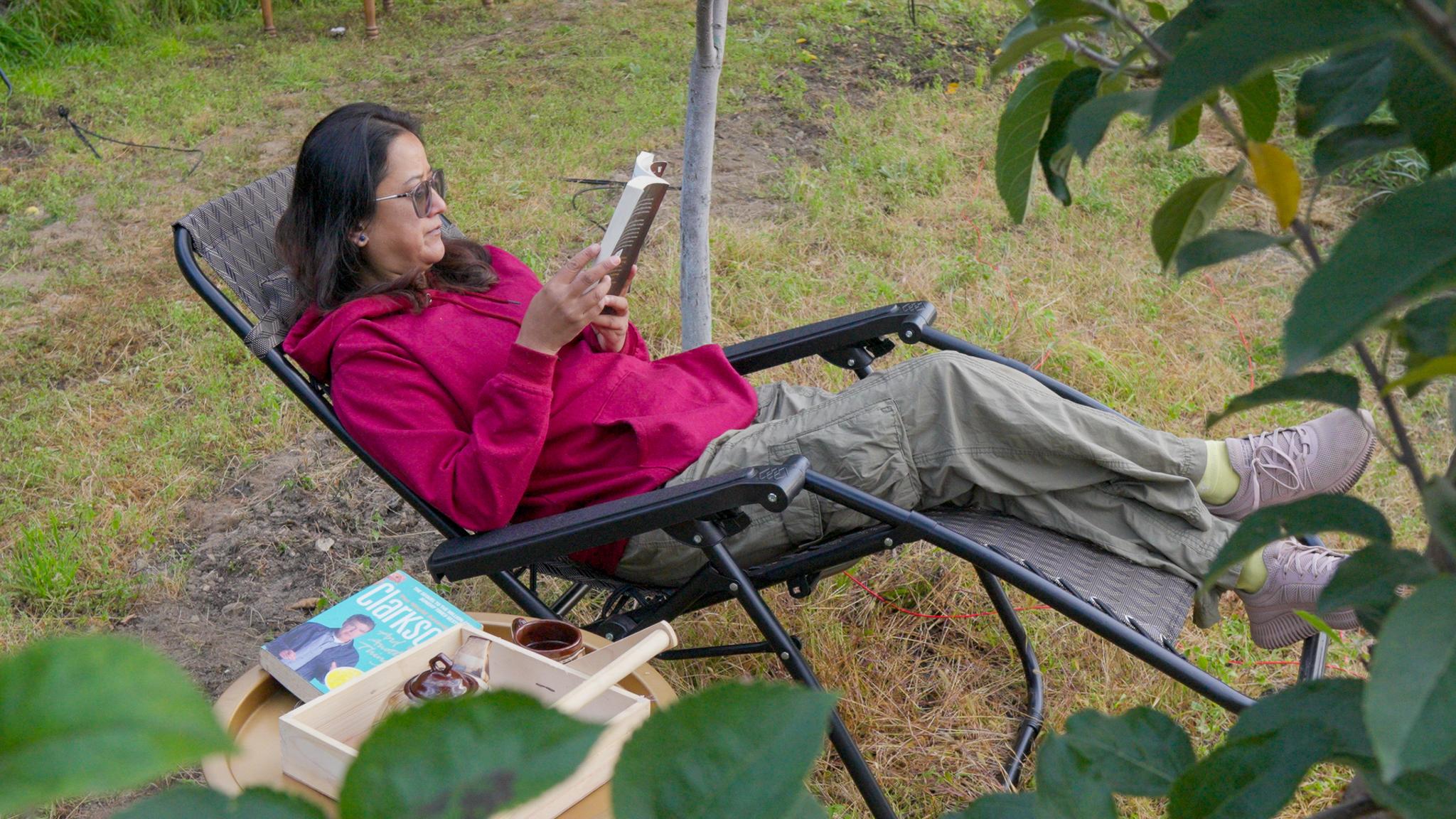 A guest reading while relaxing among the apple trees