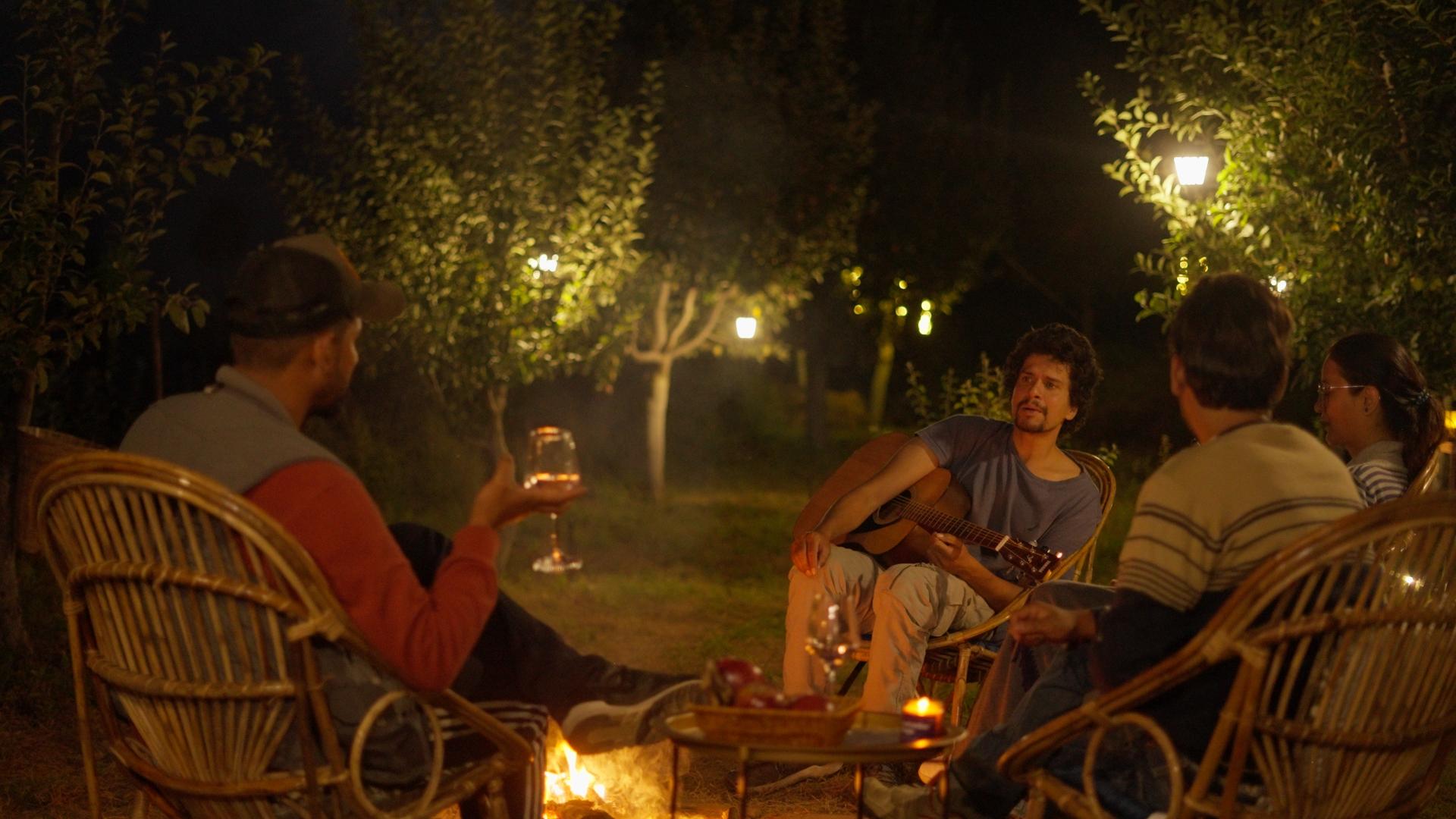 Guests sharing a fireside sundowner in an apple orchard