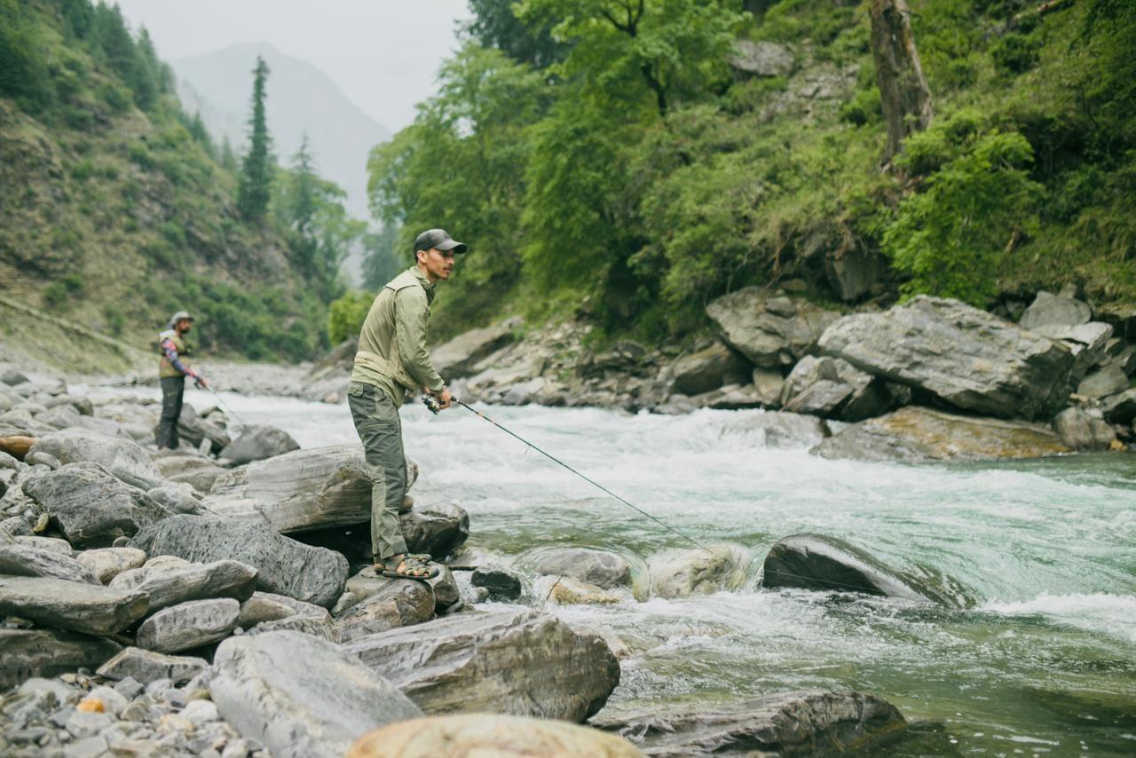 An angler casting on a clear Himachal river