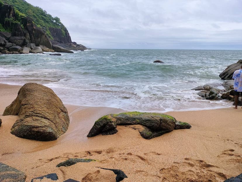 Butterfly Beach in South Goa beneath an overcast sky with choppy water and boulders