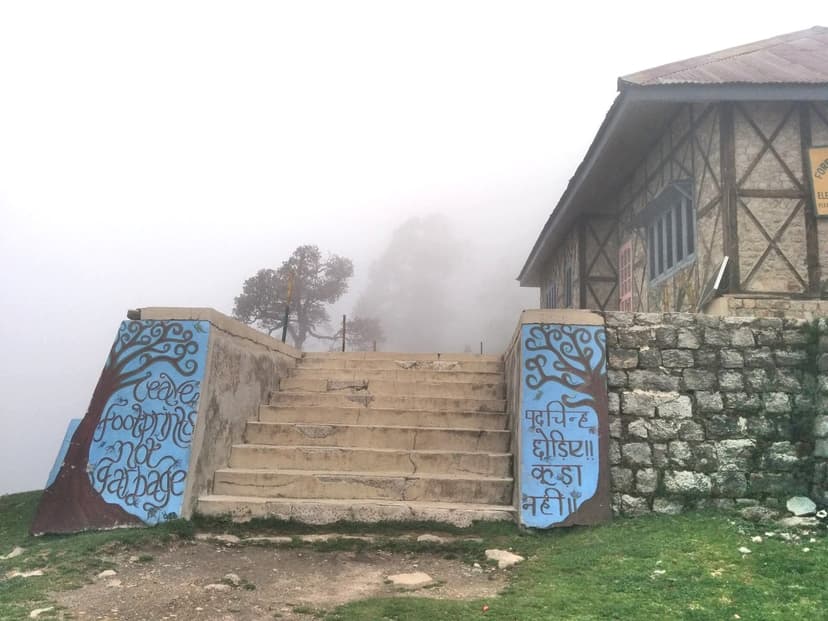 A painted mural reading Leave footprints not garbage on the misty steps at Triund