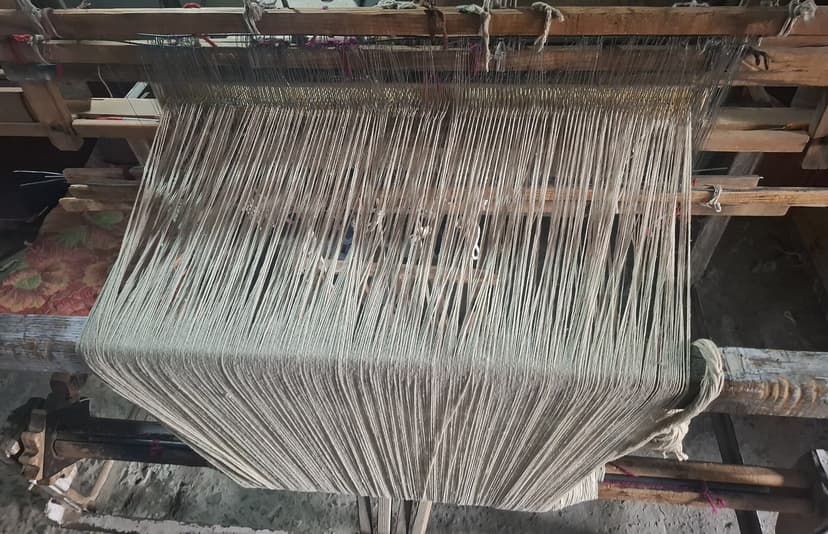 A traditional wooden Kinnaur khadi loom with natural undyed warp threads stretched across the frame
