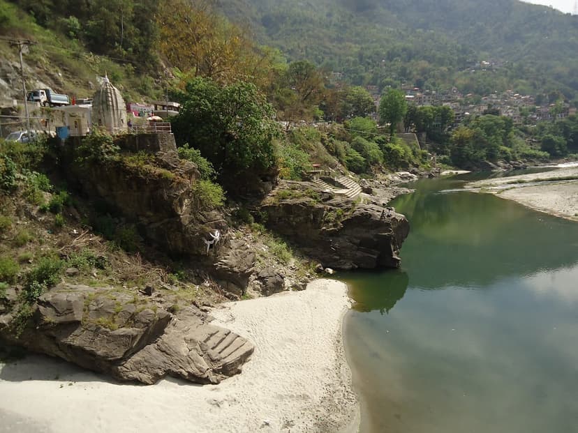 Green Beas river water, white sand bank and a small riverside shrine on rock with stone steps below Mandi town