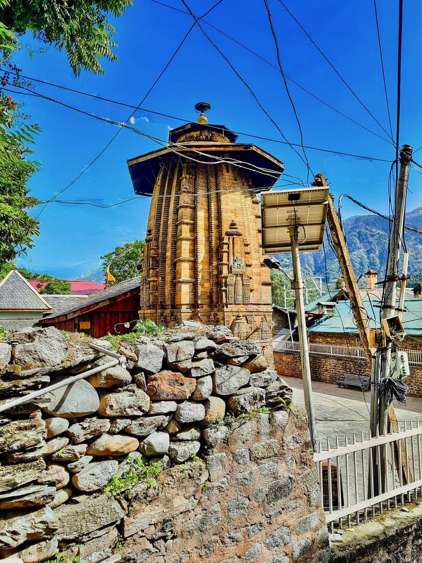 Champavati Temple in Chamba, Himachal Pradesh, tall stone shikhara-style Durga shrine with dressed stone boundary wall in the foreground and blue sky above