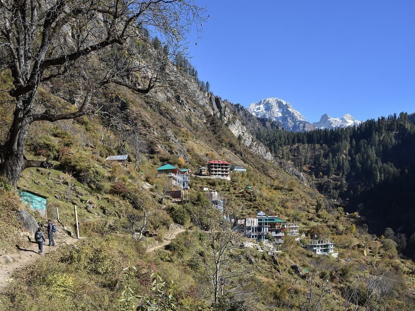 Tosh village on a forested slope below a snow peak, with the trail in the foreground