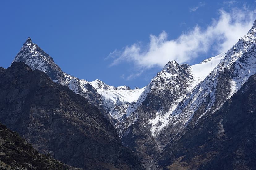 A receding glacier clinging to a col between rocky peaks in Lahaul, with brown slopes dominating the lower elevations