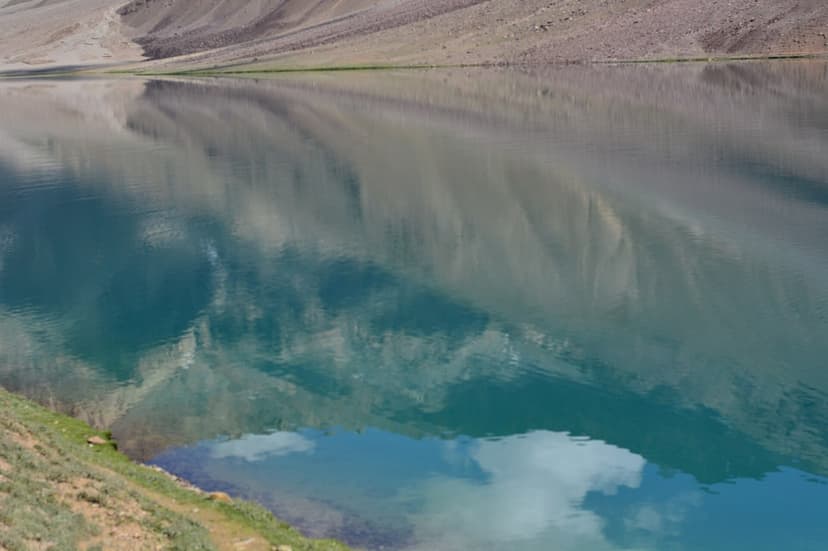 Turquoise water of Chandratal Lake at 4,300 metres in Lahaul-Spiti with sky and mountains reflecting on the still surface