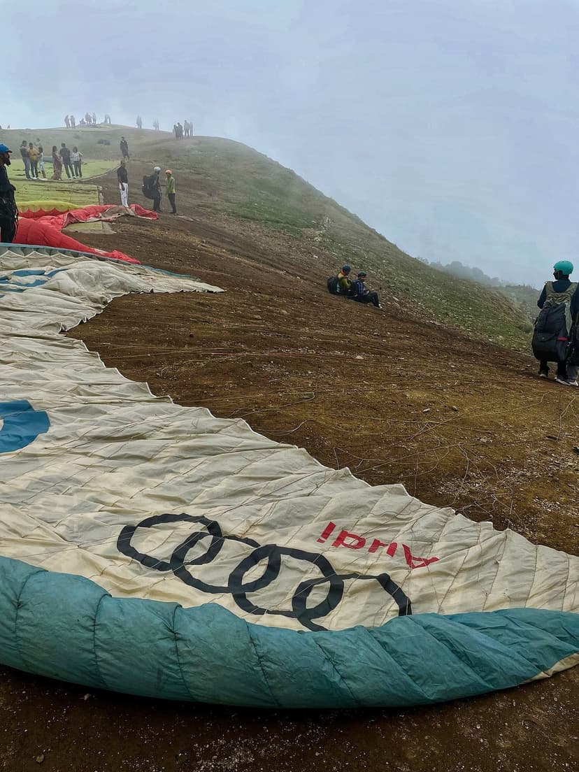 Paragliding launch with parachute spread on the ridge and pilots in the mist