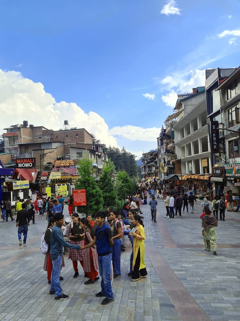 Mall Road, Manali, with shops and crowds, mountains in the background