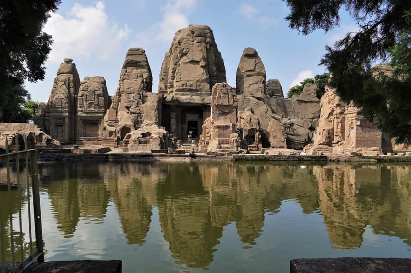 The full sandstone west face of the Masrur rock-cut temple complex reflecting in the sacred pool the early-medieval builders carved out in front