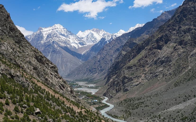 Bhaga River flowing through the Lahaul valley with snow-capped peaks and green patches of settlement, where the Halda bonfire festival marks tribal new year