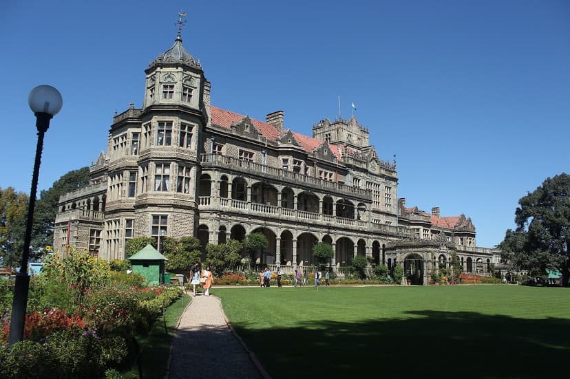 Viceregal Lodge exterior, Scottish Baronial stone building with towers and turrets, green lawns, blue sky, now Indian Institute of Advanced Study