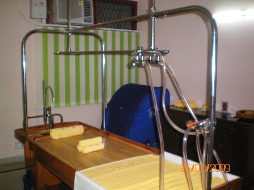 An Ayurvedic Panchakarma room with a wooden treatment table and a steam-therapy chamber