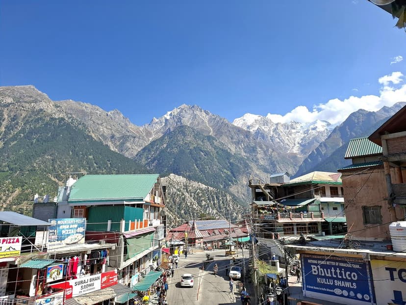 Reckong Peo market street with Pizza and shawl shops in foreground and snow-capped Kinner Kailash range behind