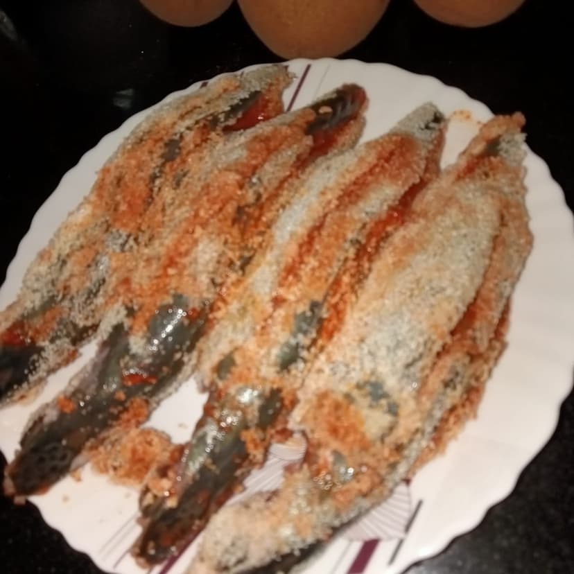 Small fish coated in semolina and stuffed with red rechado masala, ready to fry