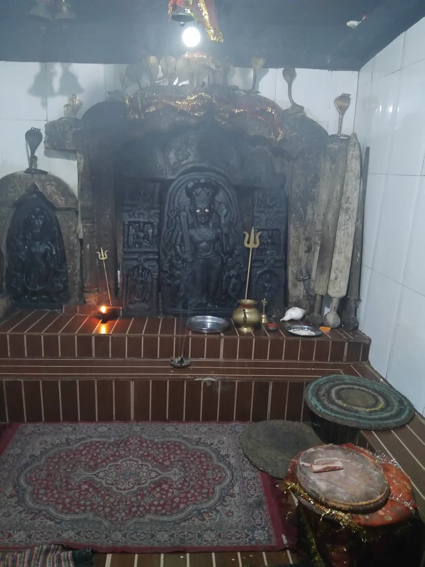 Inner sanctum of the 12th-century Khajji Nag temple at Khajjiar with black stone idols, tridents and oil lamp